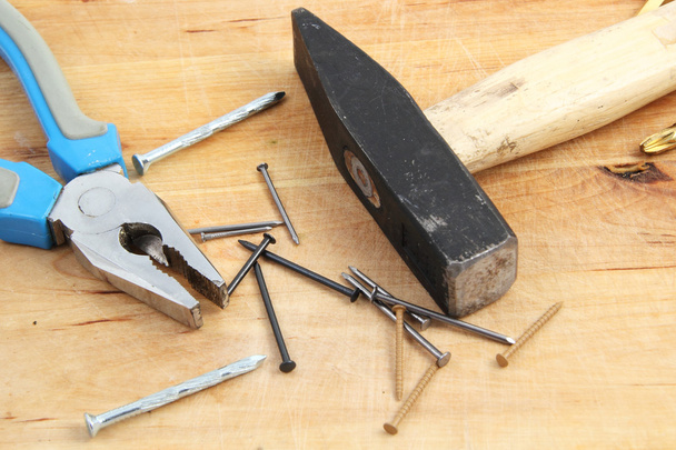 nagels, hamer en Tang op houten achtergrond - Foto, afbeelding