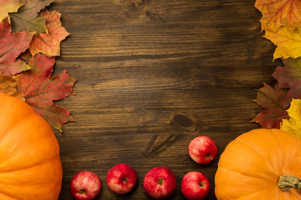 Yellow ripe pumpkin, maple leaves, red apples on wooden background. Thanksgiving, autumn. - Foto, imagen
