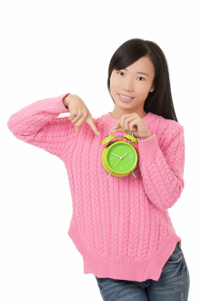 Beautiful Asian woman holding and pointing at a green alarm clock isolated on a white background - Foto, immagini