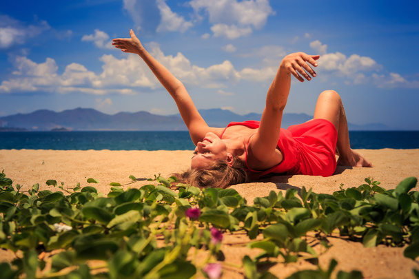 dívka v červené leží na písku zvedá ruce stranou poblíž lián - Fotografie, Obrázek