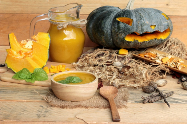 Halloween-Kürbisse und Kürbissuppe auf Holz-Hintergrund. - Foto, Bild