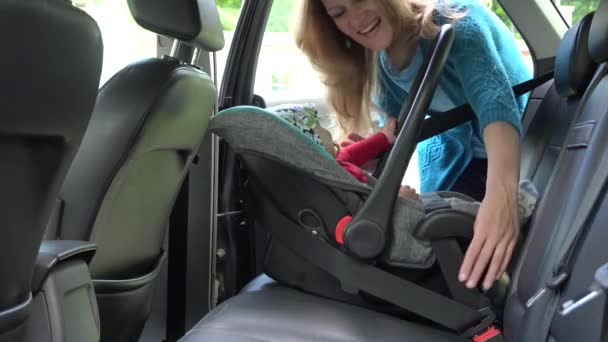 woman open car door, unfasten belt and take baby with safety seat. 4K - Filmmaterial, Video
