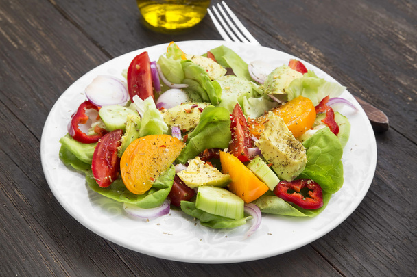 frisches Salatgericht mit Tomaten, Salat, Paprika, Zwiebeln und Avocad - Foto, Bild