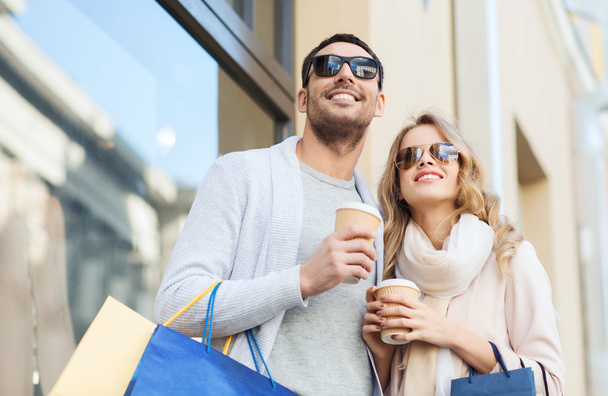 happy couple with shopping bags and coffee in city - Zdjęcie, obraz