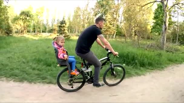 Uomo con bambino sul sedile posteriore in bicicletta nel parco
 - Filmati, video