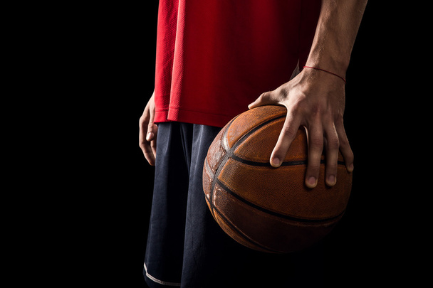 Player Holds a Basketball ball in one hand isolated on black - Foto, Imagen