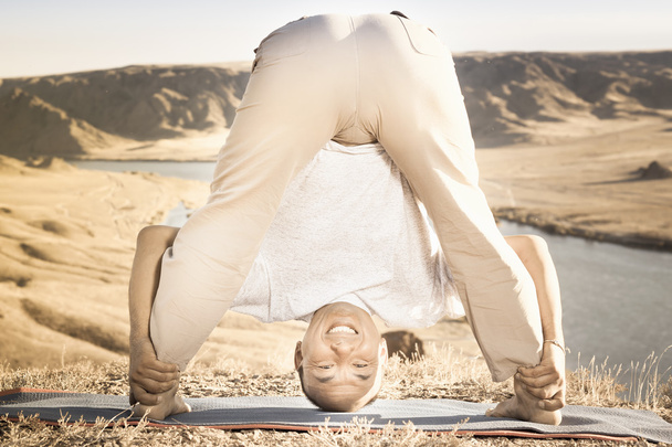 Man doing exercise of yoga outdoor above river valley - Фото, изображение