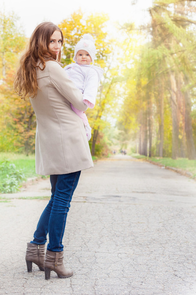 Fashion mother walking with her baby outdoor at autumn park - Zdjęcie, obraz