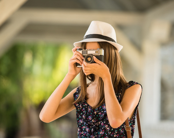 Young beautiful woman in hat is taking picture with old fashioned camera, outdoors. - Φωτογραφία, εικόνα