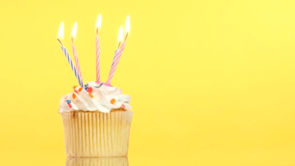 tasty birthday cupcake with five candle, on yellow background - Кадры, видео