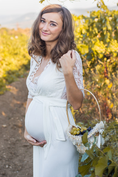 Happy pregnant woman with basket of grapes - Zdjęcie, obraz