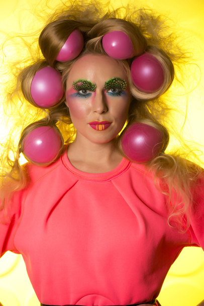 Girl with bright makeup and hair balls on a yellow background - Foto, Bild