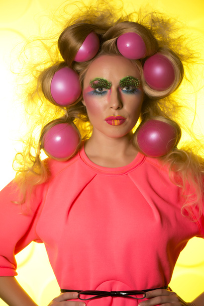 Girl with bright makeup and hair balls on a yellow background - Photo, image