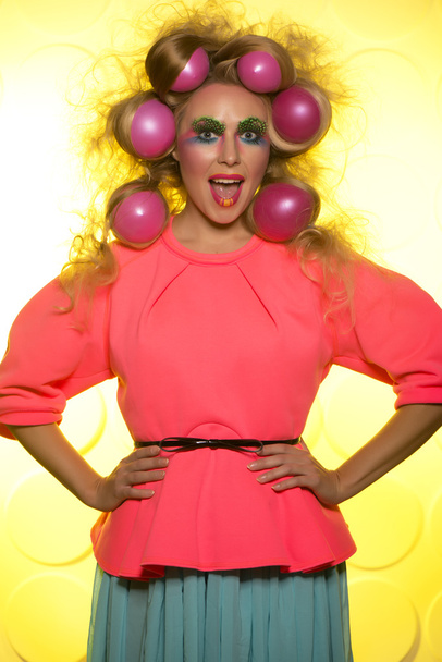 Girl with bright makeup and hair balls on a yellow background - Foto, immagini