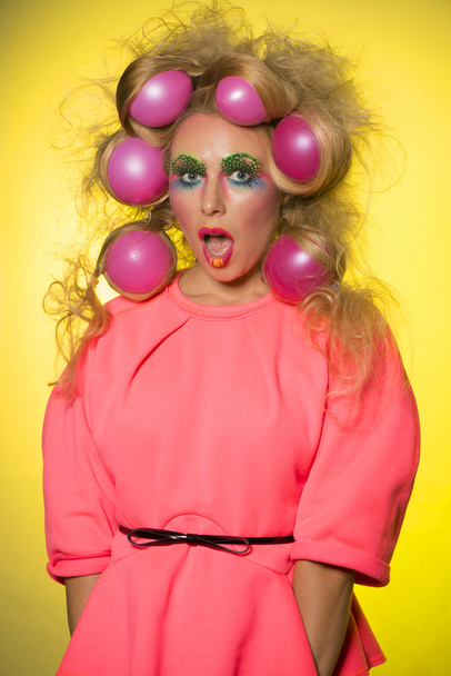 Girl with bright makeup and hair balls on a yellow background - Foto, Imagem