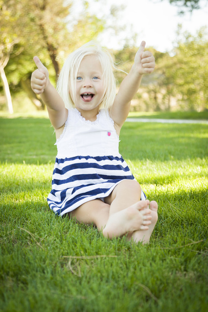 Cute Little Girl with Thumbs Up in the Grass - Fotografie, Obrázek