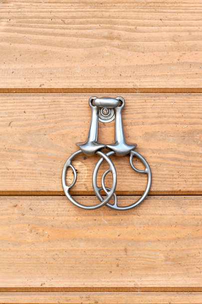 Steel horse snaffle-bit hanging on wooden background. - Fotografie, Obrázek