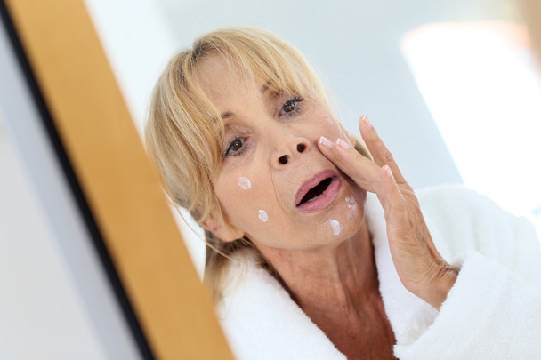 woman applying facial cream on her skin - Fotó, kép