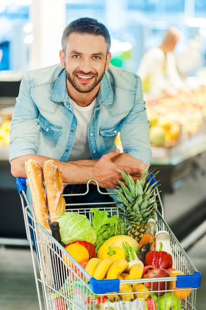 man leaning at shopping cart in store - Photo, Image