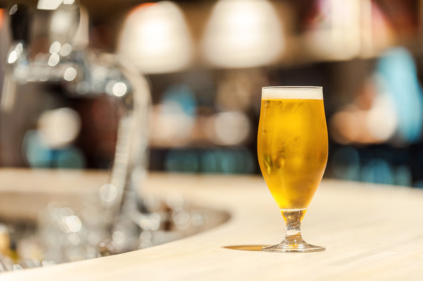 Ice cold beer. Close-up of fresh glass of beer standing on bar counter - 写真・画像