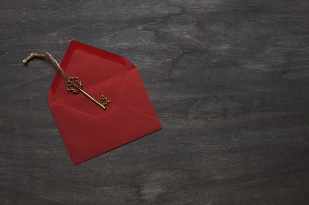 Red envelope on wood background with key - 写真・画像
