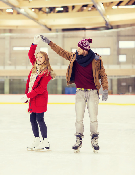 happy couple holding hands on skating rink - Zdjęcie, obraz