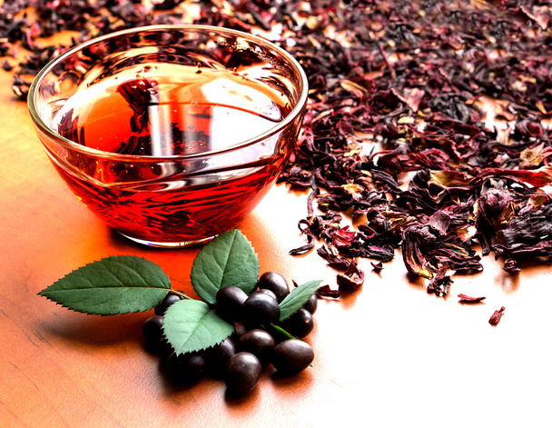 Stillleben Tasse schwarzen Tee mit Minzblättern auf getrocknetem Karkadetee hohen Kontrast Hintergrund - Foto, Bild