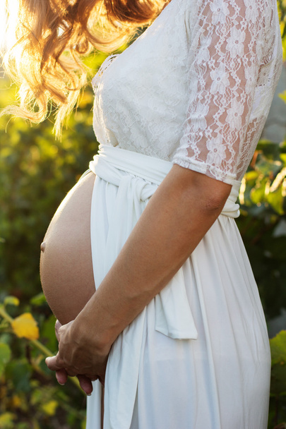 Vientre de niña embarazada en el jardín con uvas
 - Foto, imagen