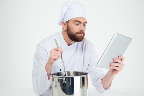 Male chef looking at digital tablet while preparing food - Foto, Bild