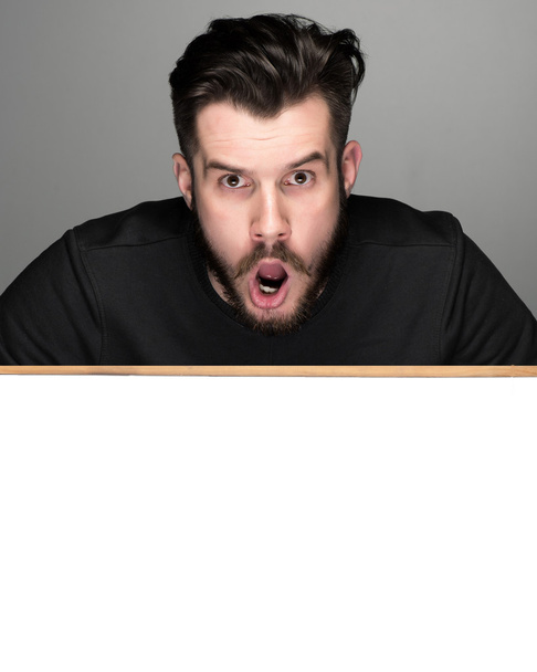 The surprised man and empty blank over gray background - Foto, imagen