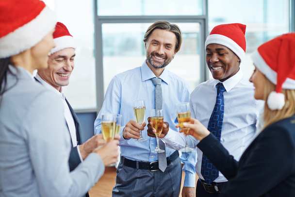 colleagues in Santa caps toasting at party - Photo, Image