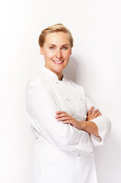 Mladá žena šéfkuchař usmívá nad bílým pozadím v šéfkuchaře oblečení. - Fotografie, Obrázek