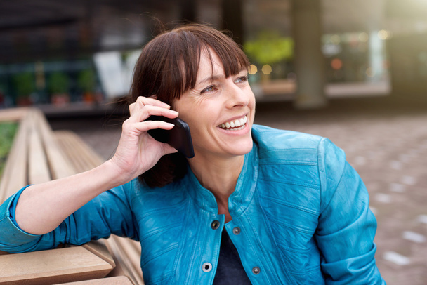 Nainen hymyilee ja kuuntelee matkapuhelinta
 - Valokuva, kuva