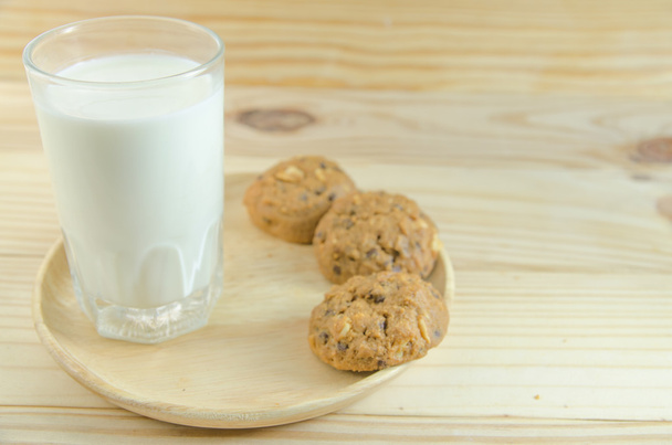 melk en cookie op houten plank achtergrond - Foto, afbeelding