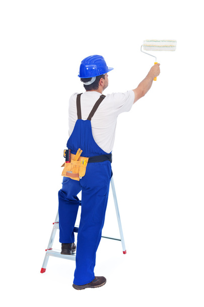 Handyman or worker painting with roller brush leaning on ladder - Φωτογραφία, εικόνα