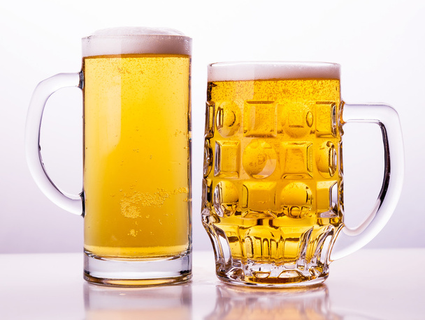 キャップの泡と新鮮なビールの 2 つのマグカップ - 写真・画像