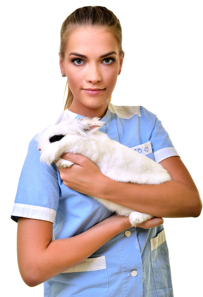 Sonriente veterinario sosteniendo y examinando lindo conejo blanco
 - Foto, imagen