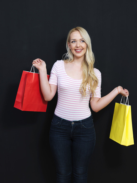 Blonde girl with shopping bags on a chalkboard background - Foto, afbeelding