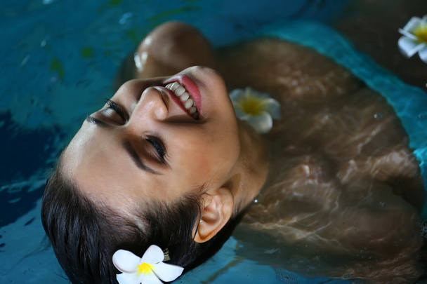 Beautiful young woman with flowers at swimming pool - Фото, зображення