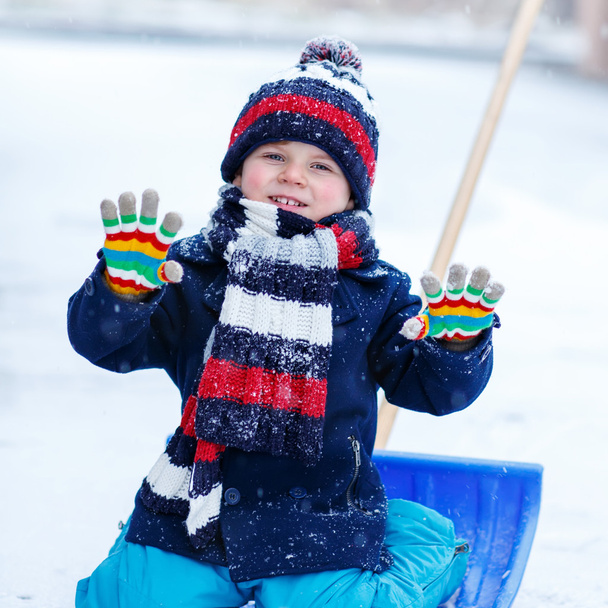 Χαριτωμένο μικρό αγόρι αστείο σε πολύχρωμα χειμερινά ρούχα διασκεδάζοντας με - Φωτογραφία, εικόνα