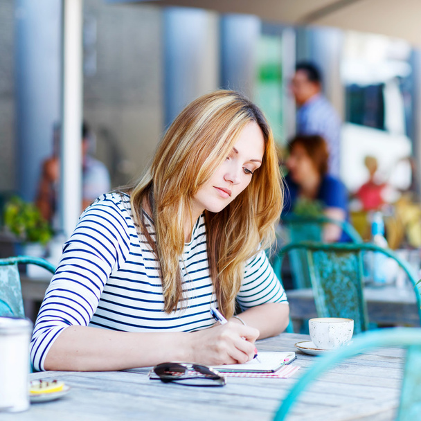 Žena, pití kávy a psaní poznámek v kavárně - Fotografie, Obrázek