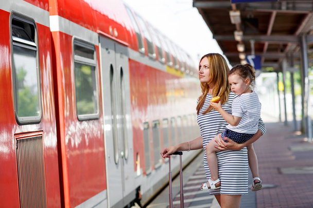 Cute little girl and mother on a railway station. - Foto, afbeelding