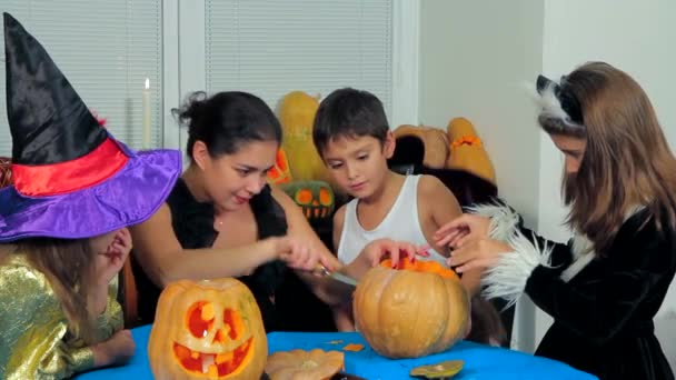 Mujer con niños tallando calabazas de Halloween
 - Imágenes, Vídeo