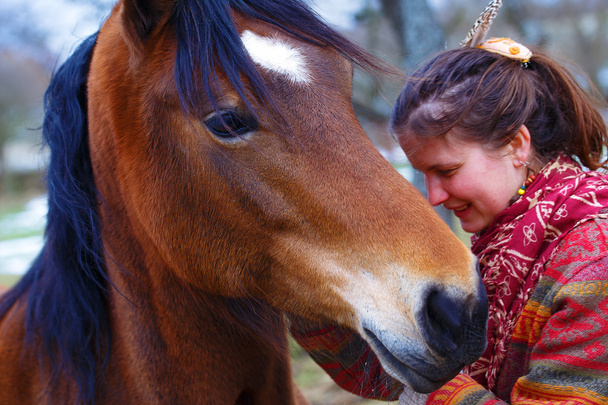 mujer retrato y caballo en el exterior. mujer abrazando a un caballo y tiene plumas en el pelo
 - Foto, Imagen