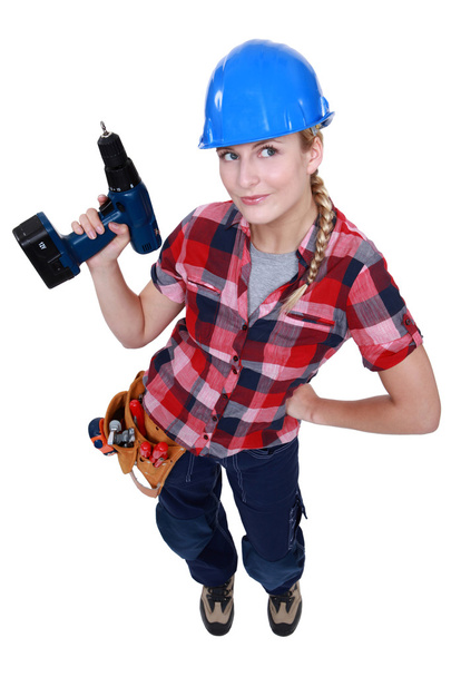 A female construction worker holding a drill. - Фото, изображение