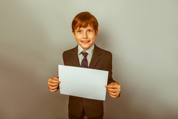 ένα αγόρι δώδεκα Ευρωπαϊκής εμφάνιση σε ένα κοστούμι που κατέχουν ένα κενό sh - Φωτογραφία, εικόνα