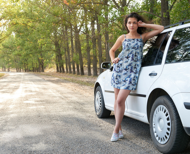 Mädchen steht neben weißem Auto auf Straße - Foto, Bild