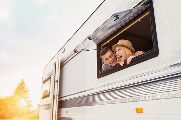 Young couple sitting in a camper van - Photo, image