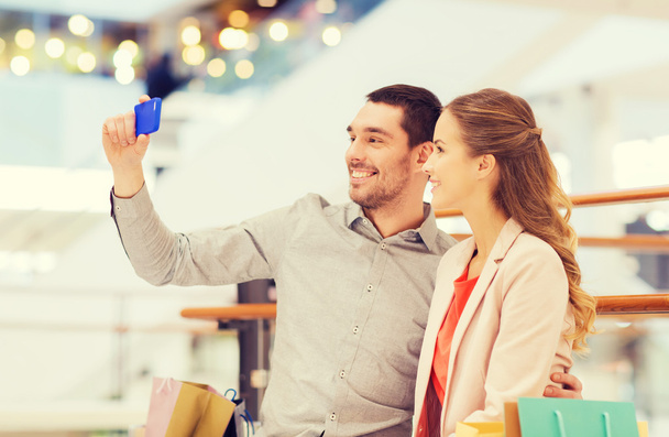 gelukkige paar met smartphone nemen selfie in winkelcentrum - Foto, afbeelding