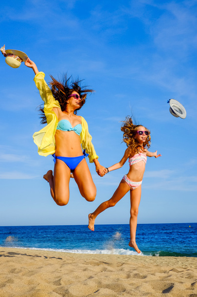 Молоді дівчата в купальнику стрибають на пляжі
. - Фото, зображення